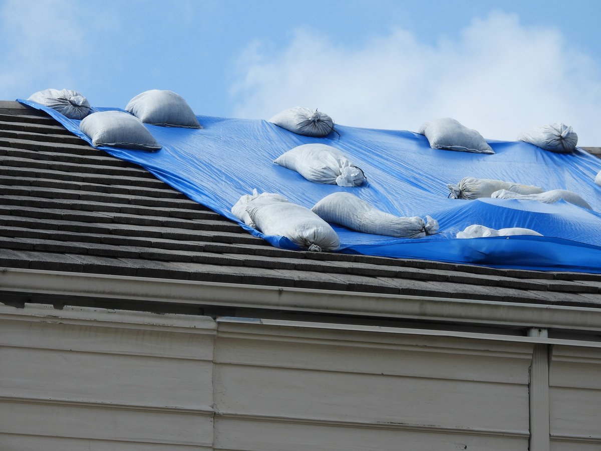 Roof tarping with sand bags to hold tarp in place after storm damage